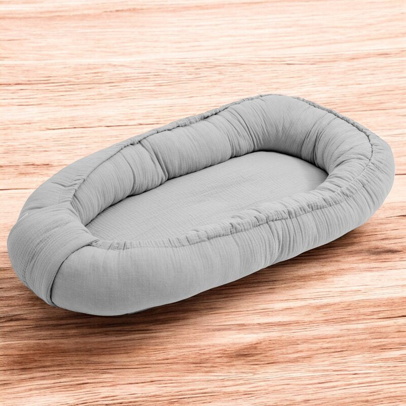 Baby nest New Baby Muselina 80x50 cm, Gri deschis – vedere pe fundal din lemn