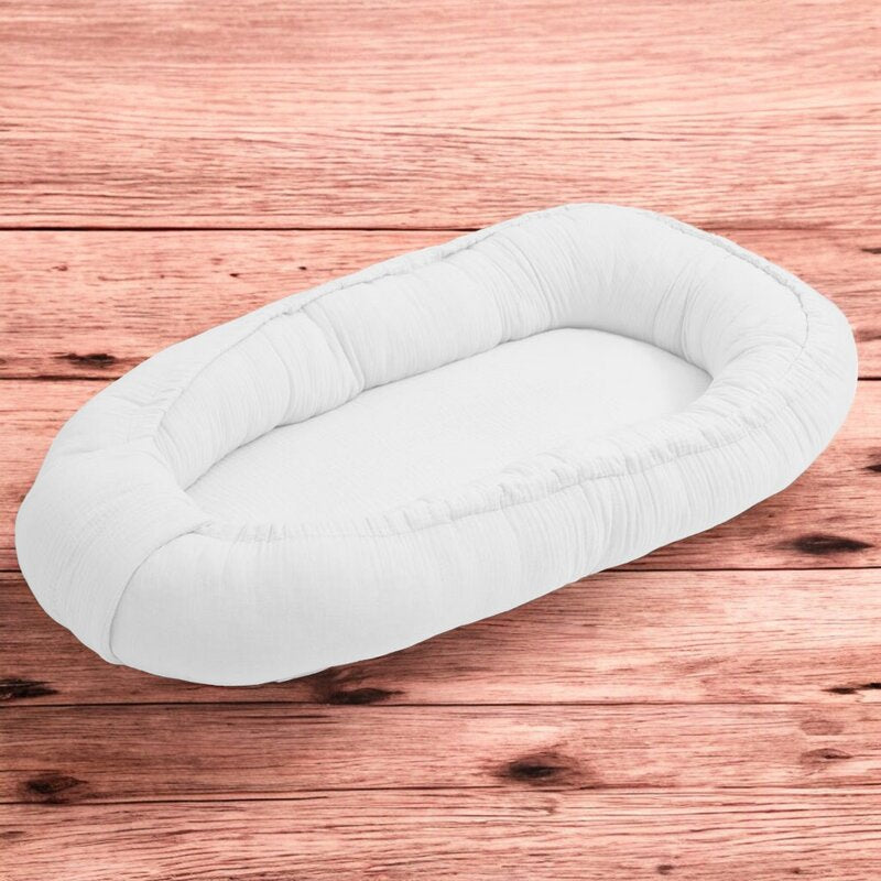 Baby nest New Baby Muselina 80x50 cm, Alb – vedere pe fundal din lemn