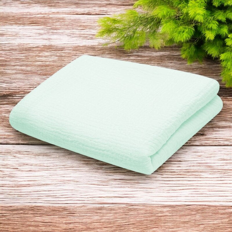 Păturică New Baby din muselină 70x100 cm mint – păturica pe o suprafață de lemn