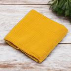 Păturică New Baby Soft Muslin mustar – păturica așezată pe lemn