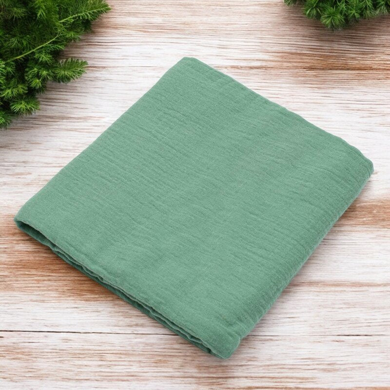 Păturică New Baby Soft Muslin verde – păturica așezată pe lemn