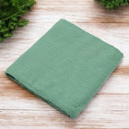 Păturică New Baby Soft Muslin verde – păturica așezată pe lemn