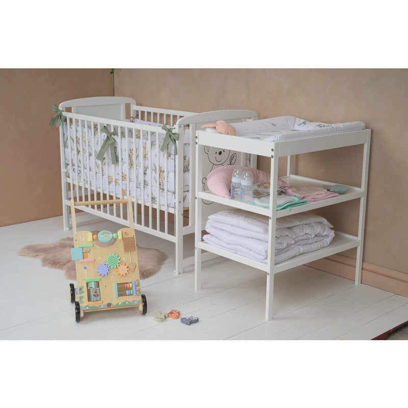 Pătuț BabyNeeds Timmi alb – pătuț amenajat cu textile, lângă o masă de înfășat